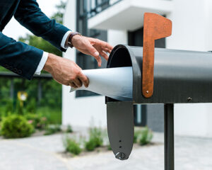 A mailbox with a pair of hands inserting a piece of paper inside